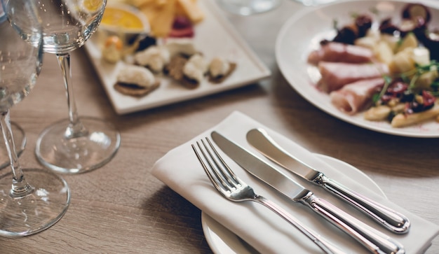 Tischbesteck, Aperitifs und Weingläser auf dem Holztisch im Restaurant.