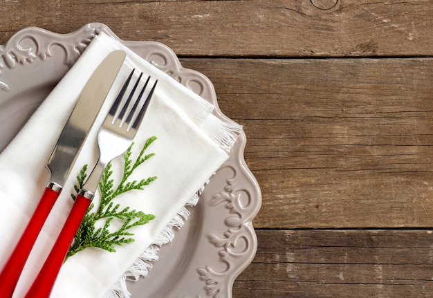 Tischdekoration - graue Platte, weiße Serviette und Gabel und Messer Draufsicht auf einem Holztisch