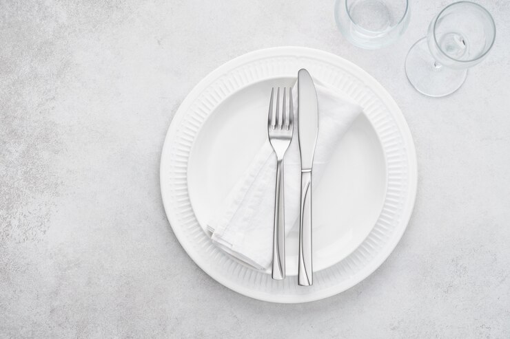 Tischdekoration im Restaurant mit weißen Tellern, Gläsern und Besteck