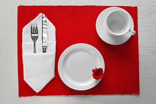 Tischdekoration mit Geschirr und Besteck auf rotem Hintergrund