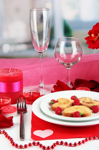 Tischdekoration zu Ehren des Valentinstags auf Zimmerhintergrund