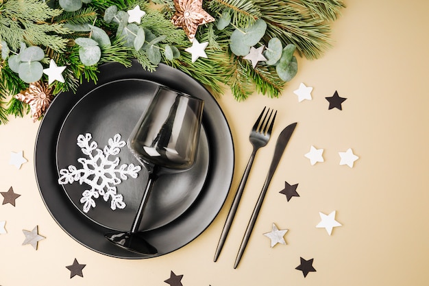 Tischdekoration zu Weihnachten. Schwarzes Geschirr und Dekoration mit Tannenzweig.