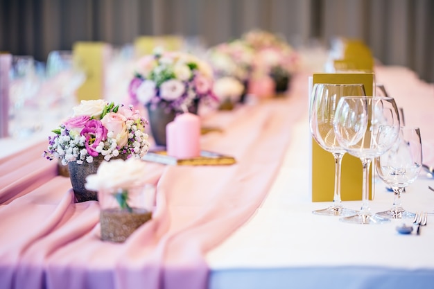 Tischdekoration zur Hochzeit. Wunderschöner Tisch mit Blumen und Glasbechern für eine festliche Veranstaltung, Party oder Hochzeitsfeier.