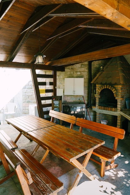 Tische und Bänke stehen in einem hölzernen Gazebo in der Nähe des Herds im Innenhof des Hauses