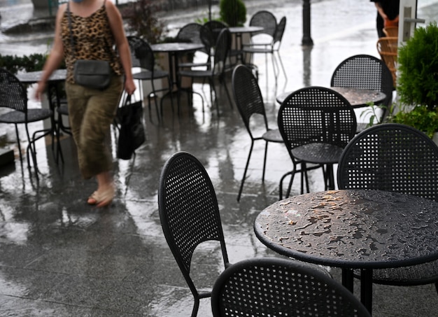 Tische und Stühle eines Straßencafés nass vom Regen