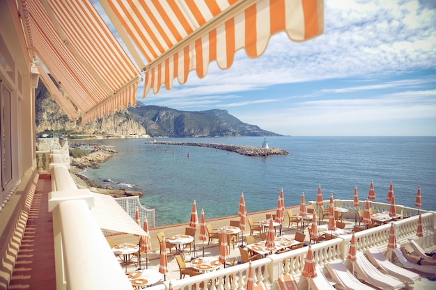 Tische und Stühle mit Liegestühlen in einem Luxushotel am Meer gegen den Himmel in Monte Carlo