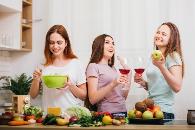 Tischgesellschaft. Tolle Zeit zusammen. Freundschaft macht Spaß. Lächelnde Frauen trinken Rotweingläser und essen gesunde Lebensmittel.