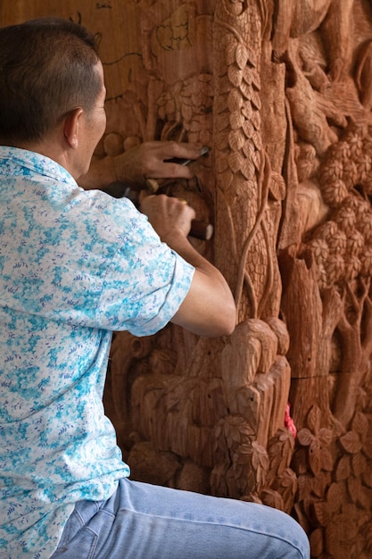 Tischler, der Holzsäulen in einem Tempel in Thailand schnitzt