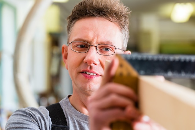 Foto tischler, der mit winkel in seiner werkstatt oder in zimmerei arbeitet