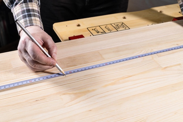 Tischler mit Bleistift markiert Größe auf Holzbrett