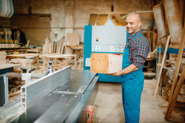 Tischler verarbeitet Holzbalken auf Hobelmaschine, Holzbearbeitung, Holzindustrie, Zimmerei.