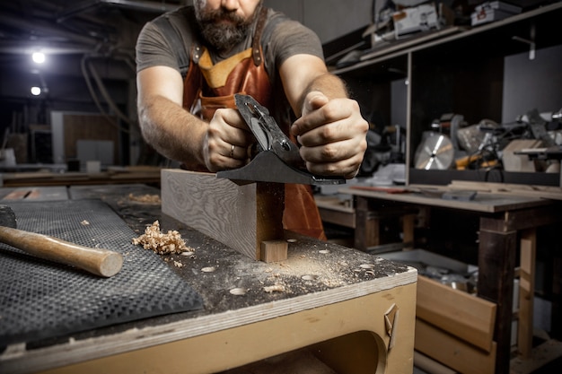 Tischlermeister in einem Schürzenbaum mit einem Flugzeug in der Werkstatt hautnah