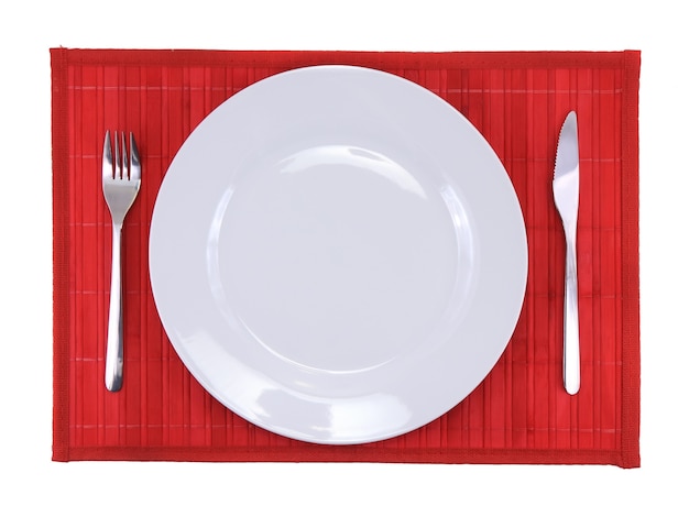 Tischserviermesser, Teller, Gabel auf rotem Hintergrund.