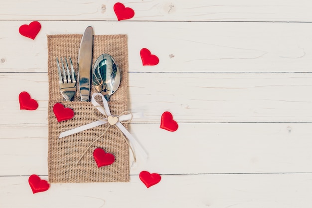 Tischset zum Feiern Valentinstag. Hölzerne Tisch Platz Einstellung und Besteck mit roten Herzen für Valentinstag.