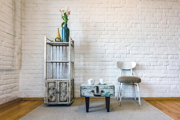 Tischstühle Regale auf dem Hintergrund einer weißen Ziegelwand im Vintage-Loft-Interieur