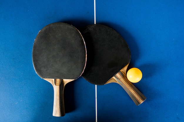 Tischtennisschläger und Ball auf blauem Hintergrund.