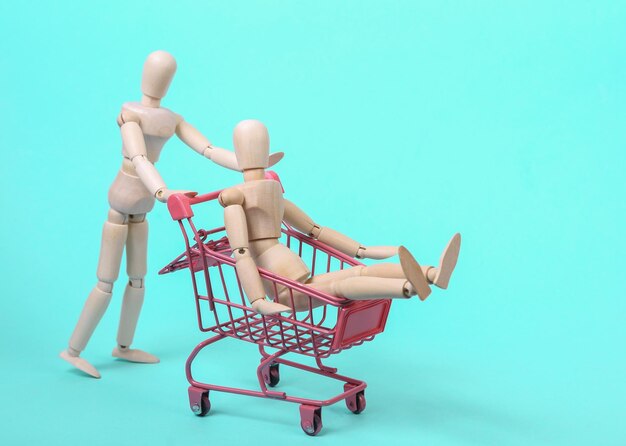 Títeres con un mini carrito de compras sobre un fondo azul Concepto de compras