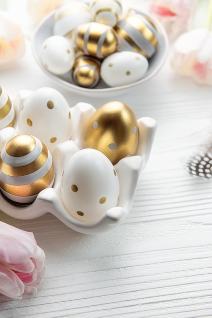 Titular con huevos de Pascua pintados de colores dorados sobre un fondo blanco de madera