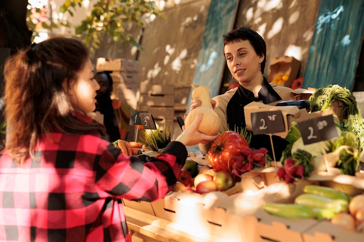 Foto titular de un puesto femenino que vende bioproductos orgánicos frescos en el stand, hablando con el cliente sobre alimentación saludable y verduras naturales locales. mujer joven preguntando al propietario de una pequeña empresa sobre productos ecológicos.