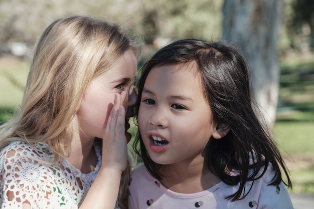 Étnicas mistas meninas brincando crianças sussurrando chinês no parque