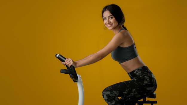 Étnico indio mujer deportiva fuerte chica atlética ciclismo flexión ciclismo en equipo de bicicleta de ejercicio