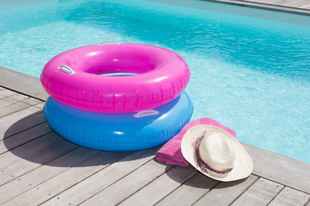 Toalha colorida e bóia azul e rosa perto da piscina