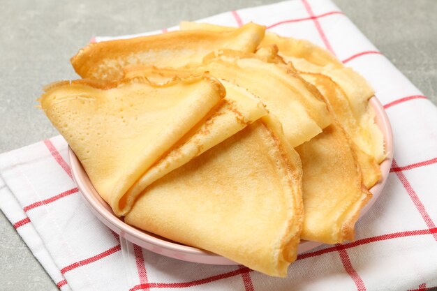 Toalha de cozinha com prato de panquecas finas na mesa cinza