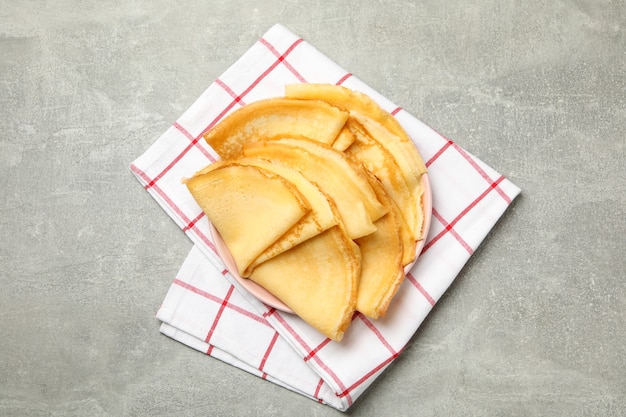 Toalha de cozinha com prato de panquecas finas na mesa cinza