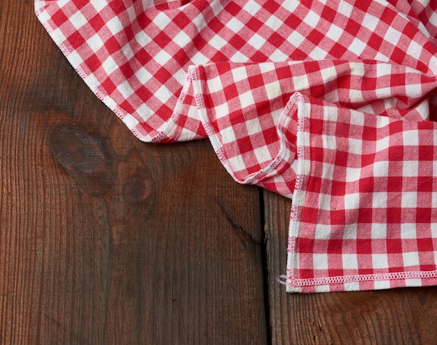 Toalha de cozinha de tecido vermelho e branco em uma mesa de madeira marrom