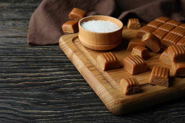 Toalha de cozinha e tábua com pedaços de caramelo e sal na mesa de madeira