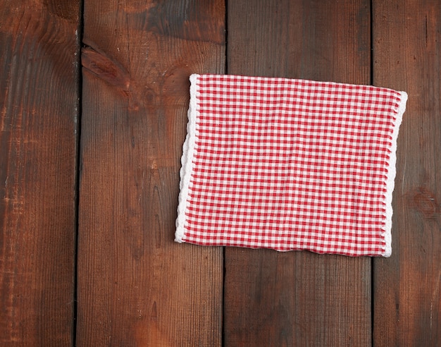 Foto toalha de cozinha quadriculada vermelha branca sobre uma superfície de madeira marrom