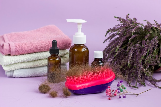 Toalha de escova de cabelo de garrafas de medicação e urze de ervas em fundo roxo Problema de perda de cabelo