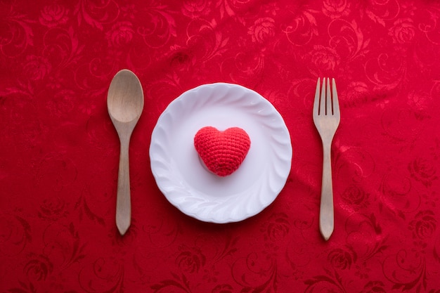 Toalha de mesa vermelha com sinal da forma do coração na placa, fundo do dia de valentim.