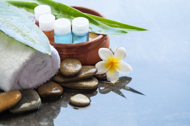 Toalha e tubo de óleo e pedra de flor em fundo preto Conceito de cuidados com o corpo e spa