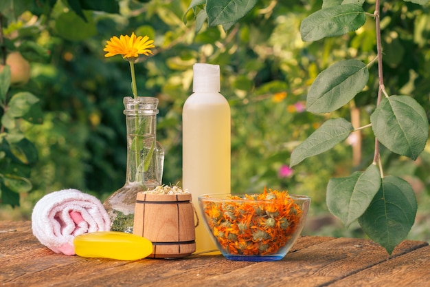 Foto toalha, sabonete e frasco plástico com extrato de calêndula, flores de calêndula.