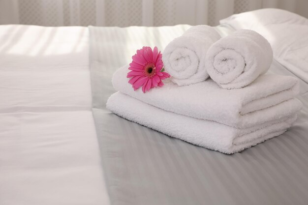 Toalhas brancas frescas com flor na cama dentro de casa espaço para texto