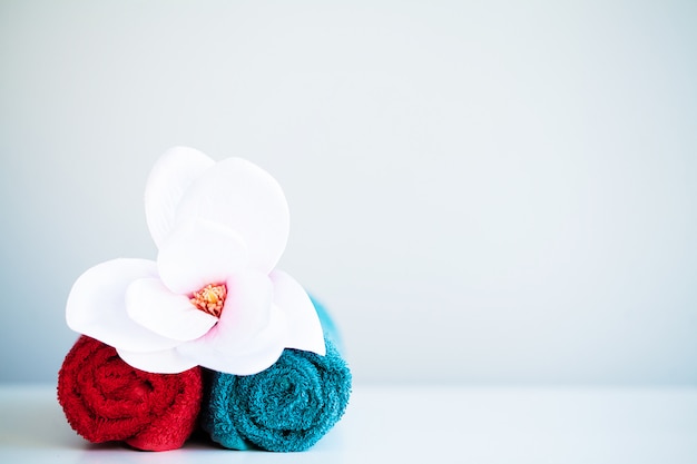 Toalhas coloridas e orquídea na mesa branca com espaço de cópia no banheiro