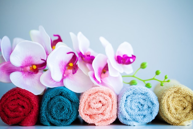 Toalhas coloridas e orquídea na mesa branca com espaço de cópia no banheiro