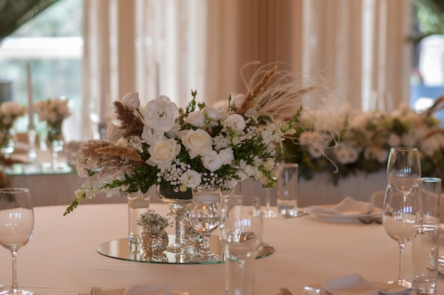 Toalhas de mesa brancas com vasos transparentes e arranjos de crisântemo e samambaia brancos