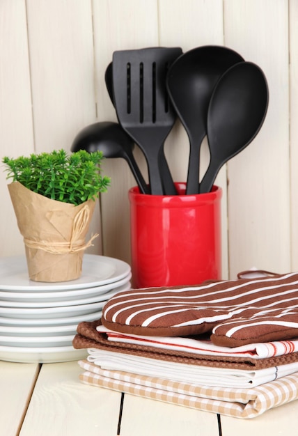 Toalhas de potholders de utensílios de cozinha e mais na mesa de madeira