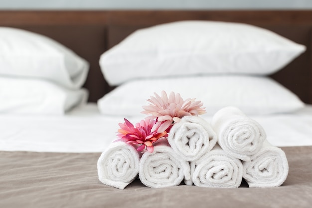 Toalhas e flores na cama no quarto do hotel