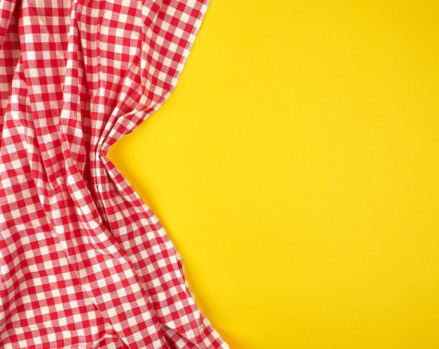 Toalla de cocina a cuadros roja blanca sobre un fondo amarillo