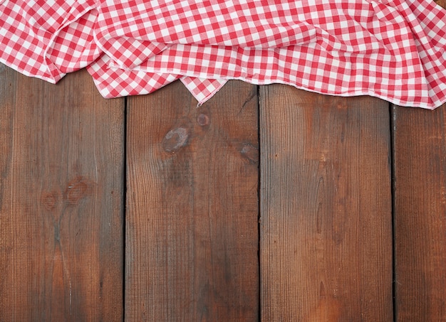 Toalla de cocina a cuadros rojo blanco sobre una mesa de madera marrón