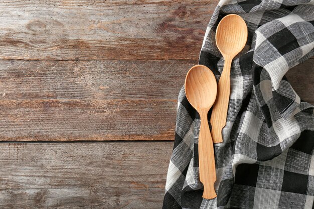 Toalla de cocina limpia y cucharas en la vista superior de la mesa de madera