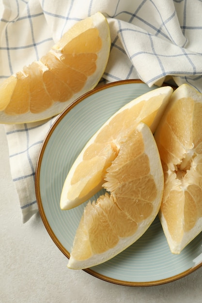 Toalla de cocina y plato con rodajas de pomelo en blanco con textura