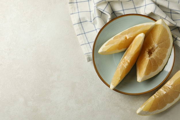 Toalla de cocina y plato con rodajas de pomelo sobre fondo blanco con textura