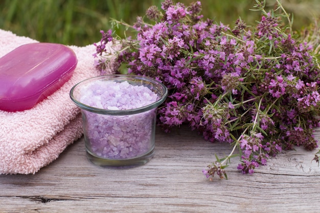 Toalla de felpa para procedimientos de baño con recipiente de vidrio de flores de tomillo con sal marina y jabón