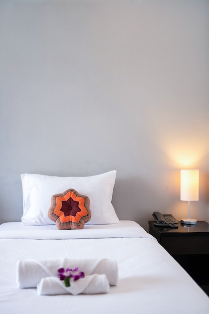 Toalla con orquídea en la decoración de la cama en el interior del dormitorio para el cliente del hotel.