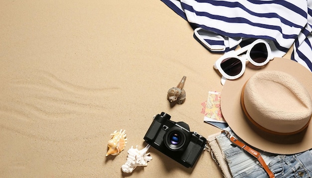 Una toalla de playa con una cámara y una concha en la arena.
