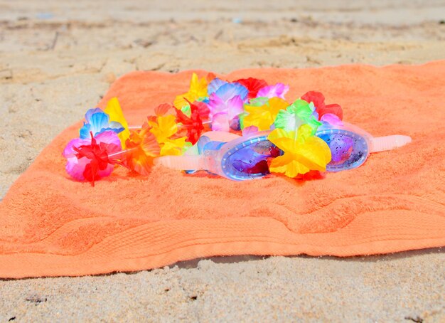 Toalla de playa naranja con gafas y collar hawaiano